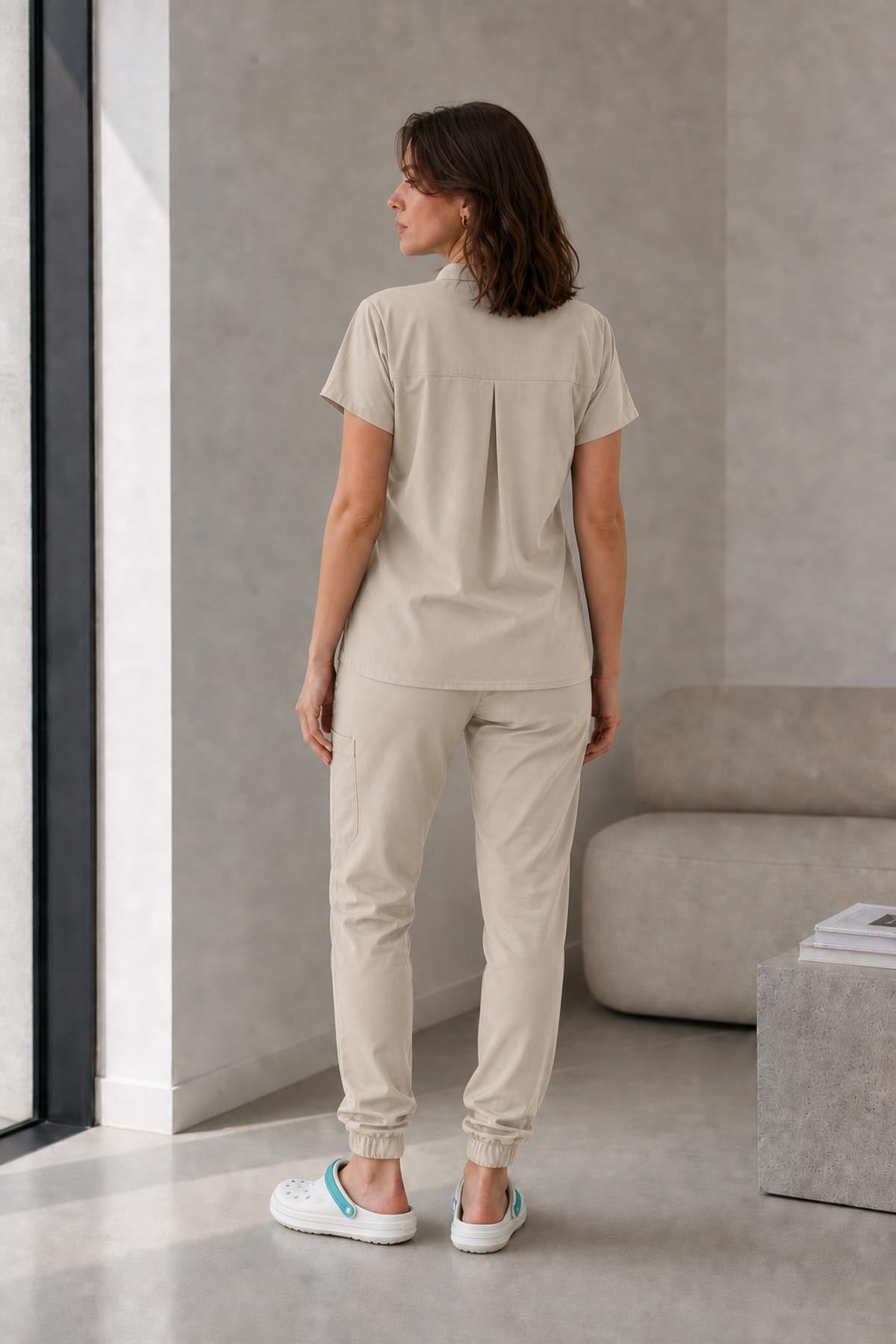 Asistenta medicala purtand bluza uniforma medicala bej unisex, model Scrub Activity, vedere din spate
