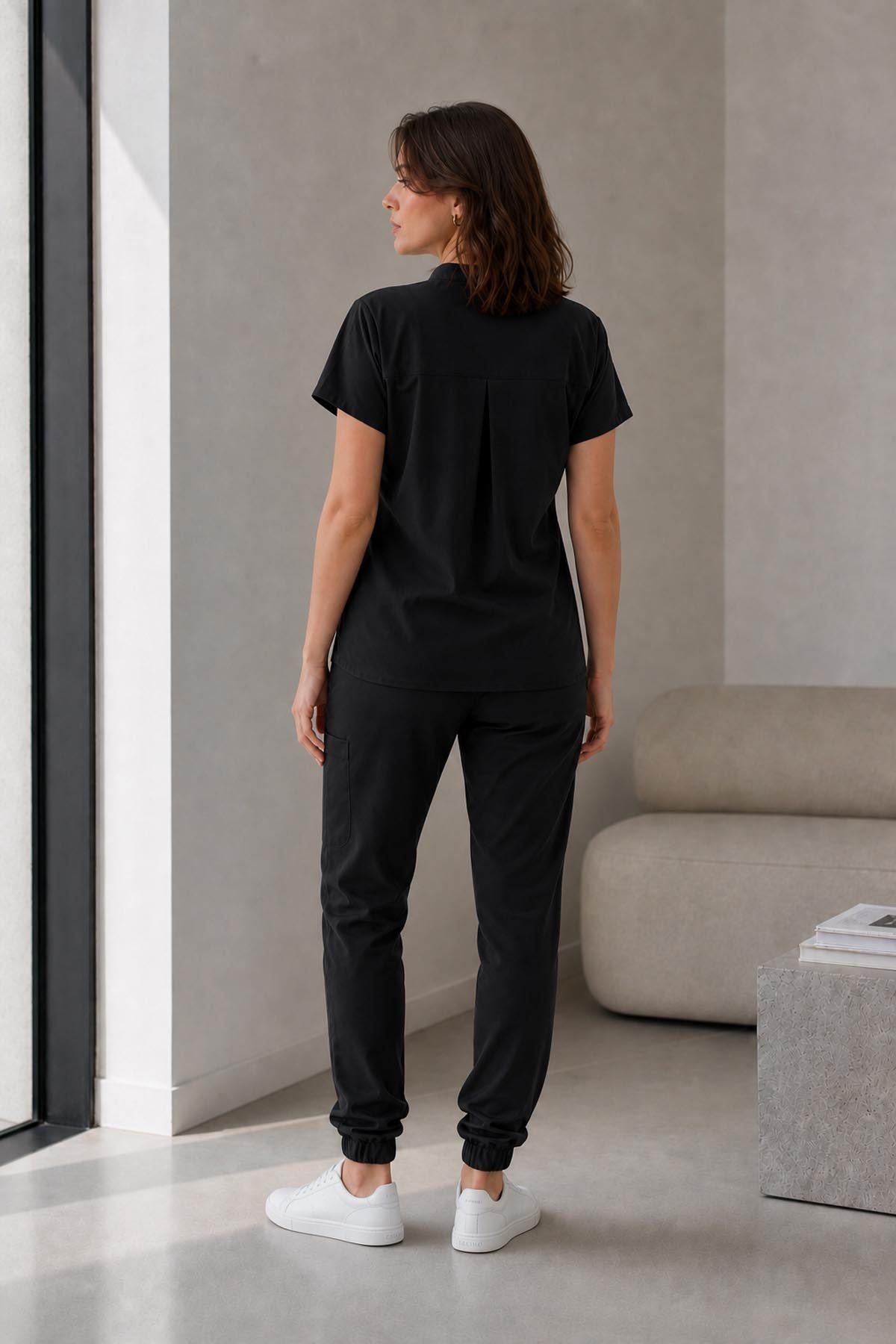 Asistenta medicala purtand bluza uniforma medicala negru unisex, model Scrub Activity, vedere din spate
