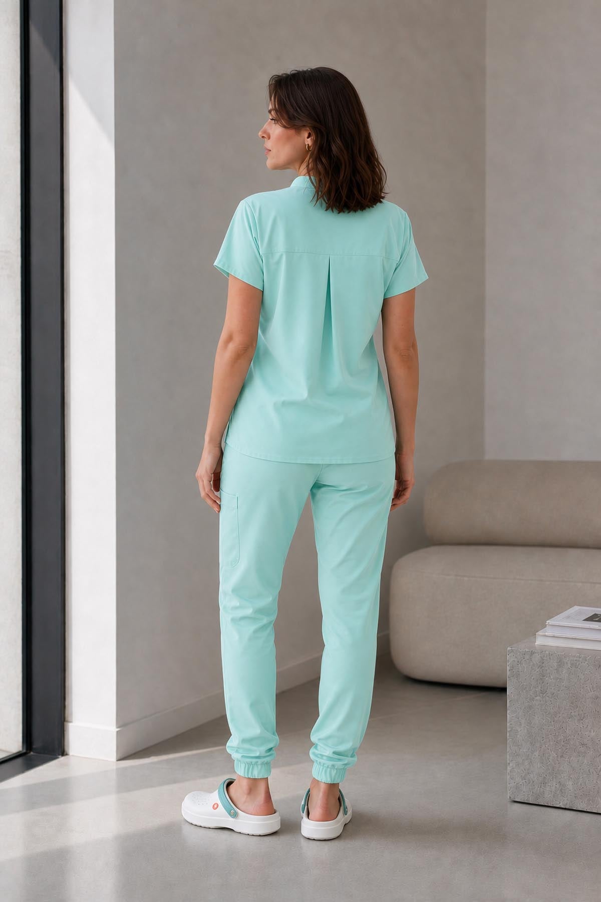 Asistenta medicala purtand bluza uniforma medicala verde menta unisex, model Scrub Activity, vedere din spate