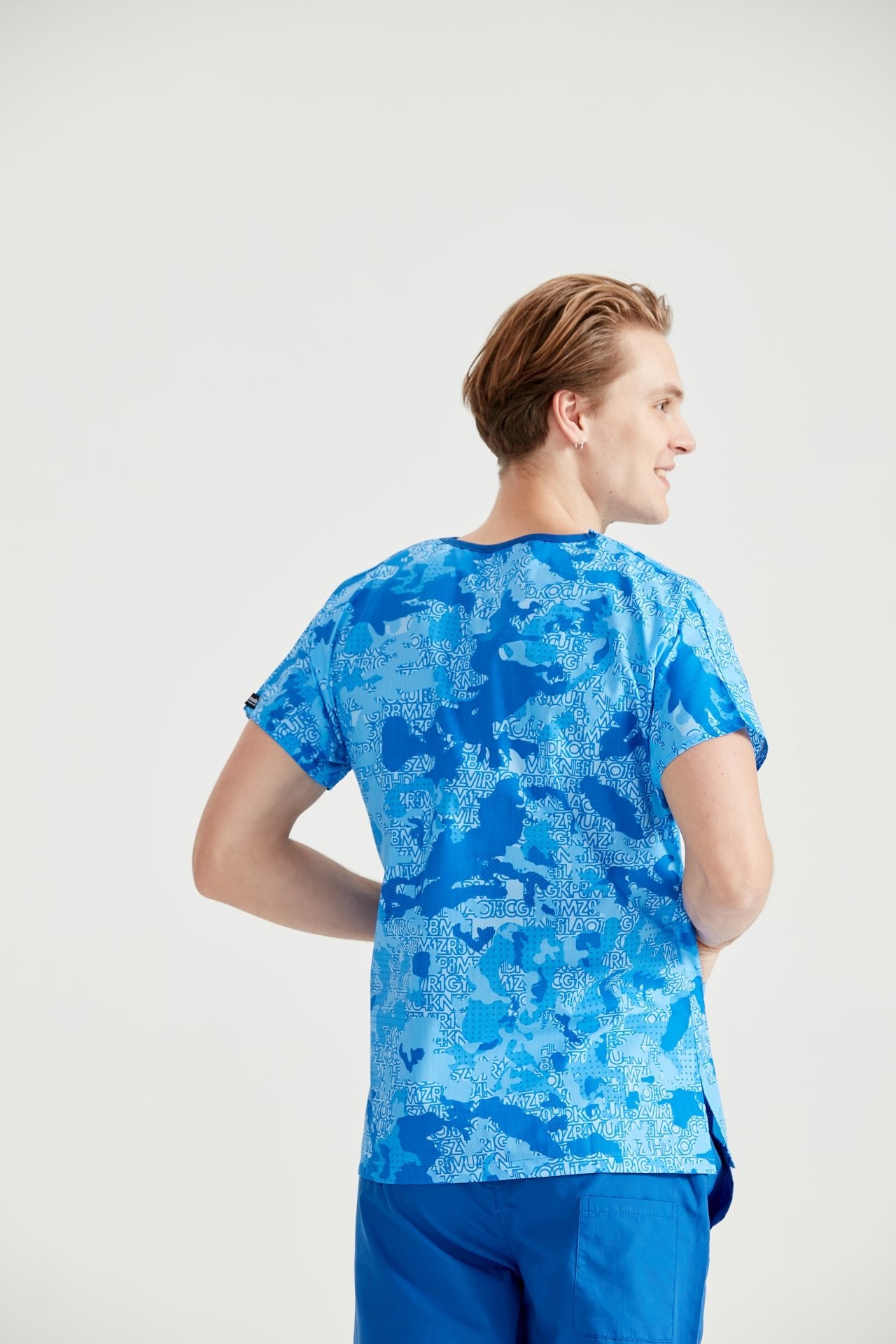 Orvosi asszisztens terepszínű kék orvosi blúzba öltözve, hátulról