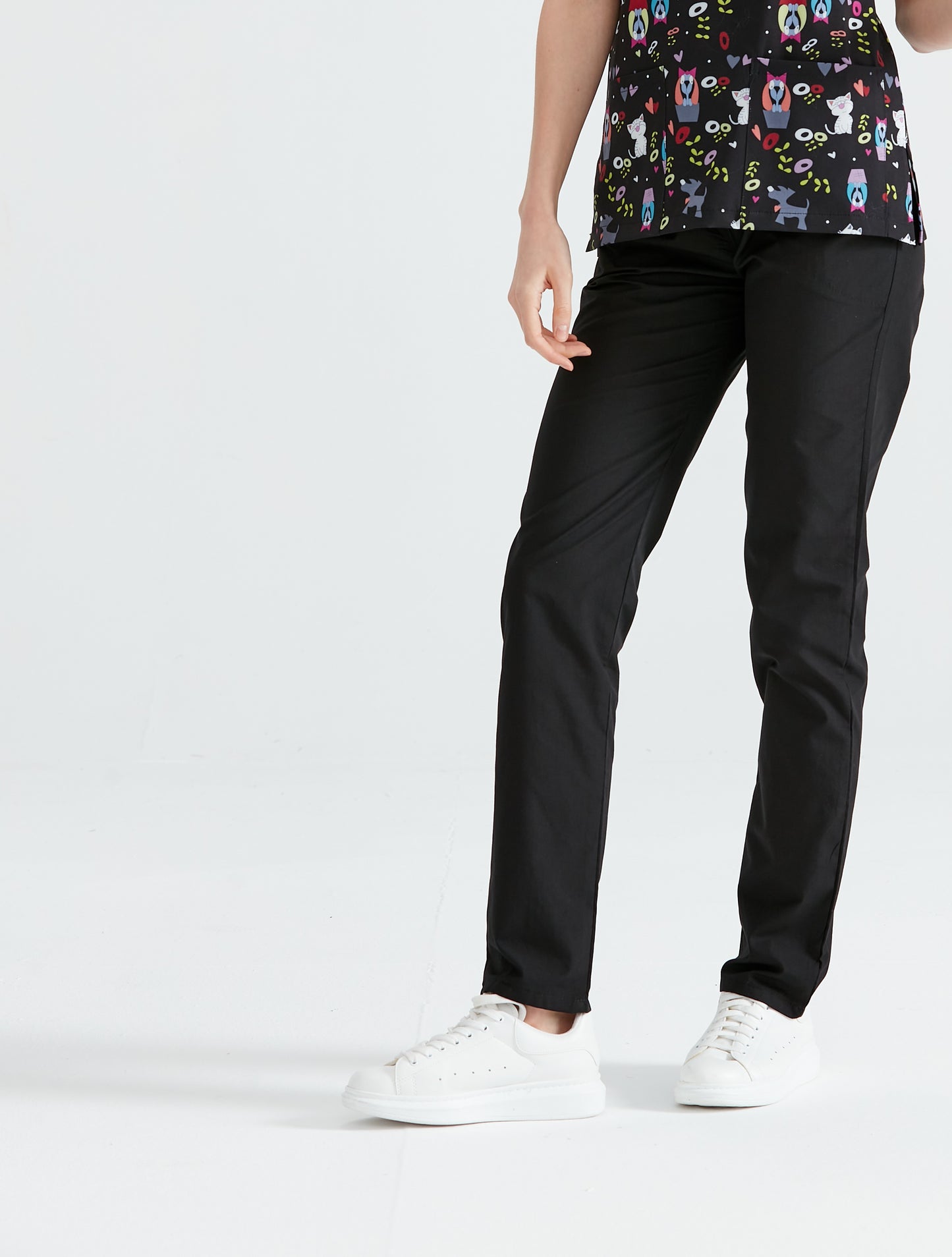 Absolut fekete nadrágba és nyomott blúzba öltözött orvosi asszisztens, elölnézet