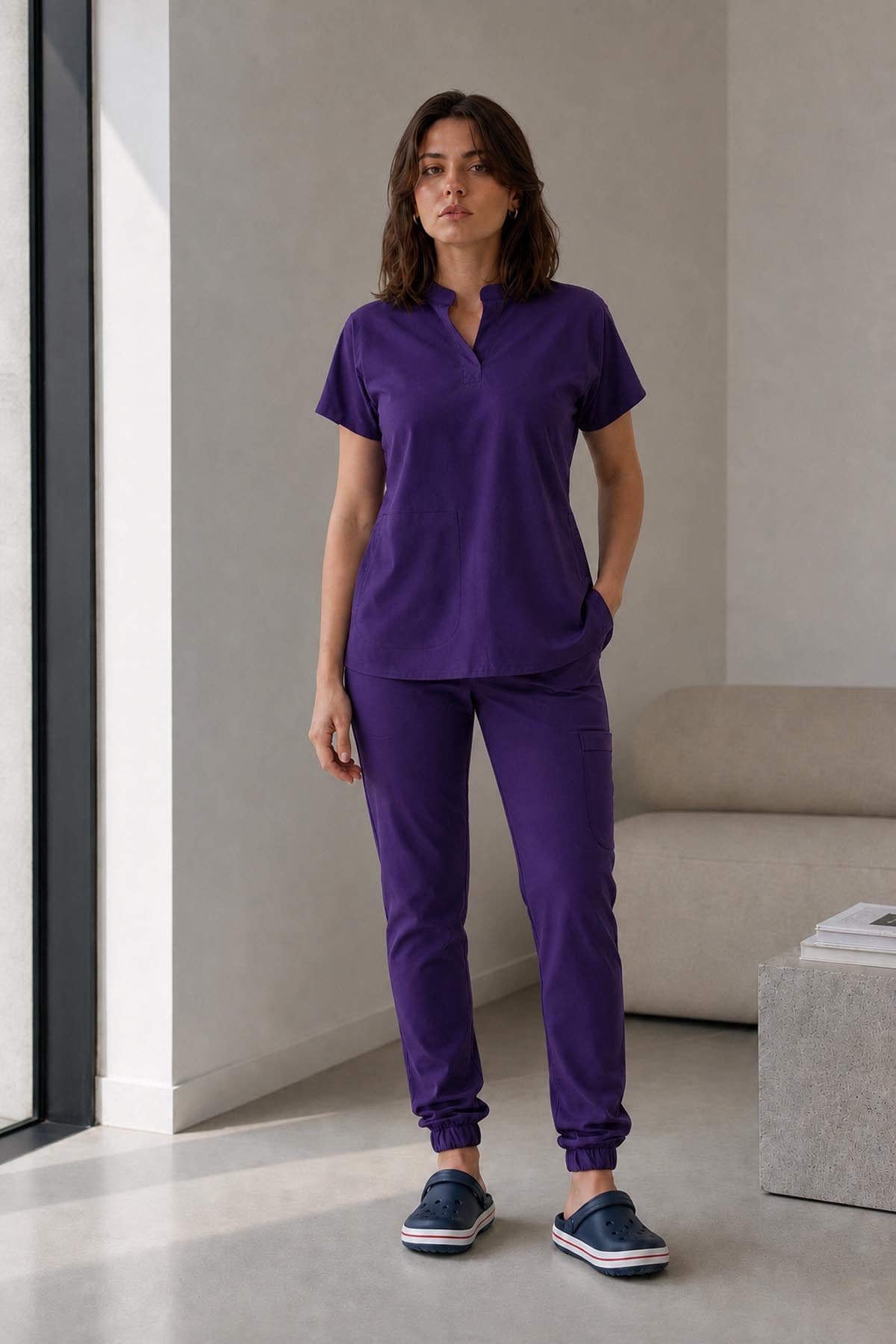 Asistenta medicala purtand bluza uniforma medicala mov unisex, model Scrub Activity, vedere din fata