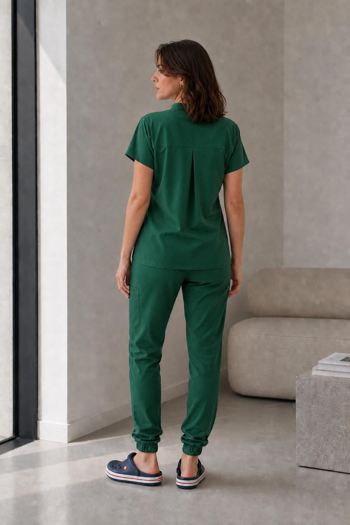 Asistenta medicala purtand bluza uniforma medicala verde kaki unisex, model Scrub Activity, vedere din spate