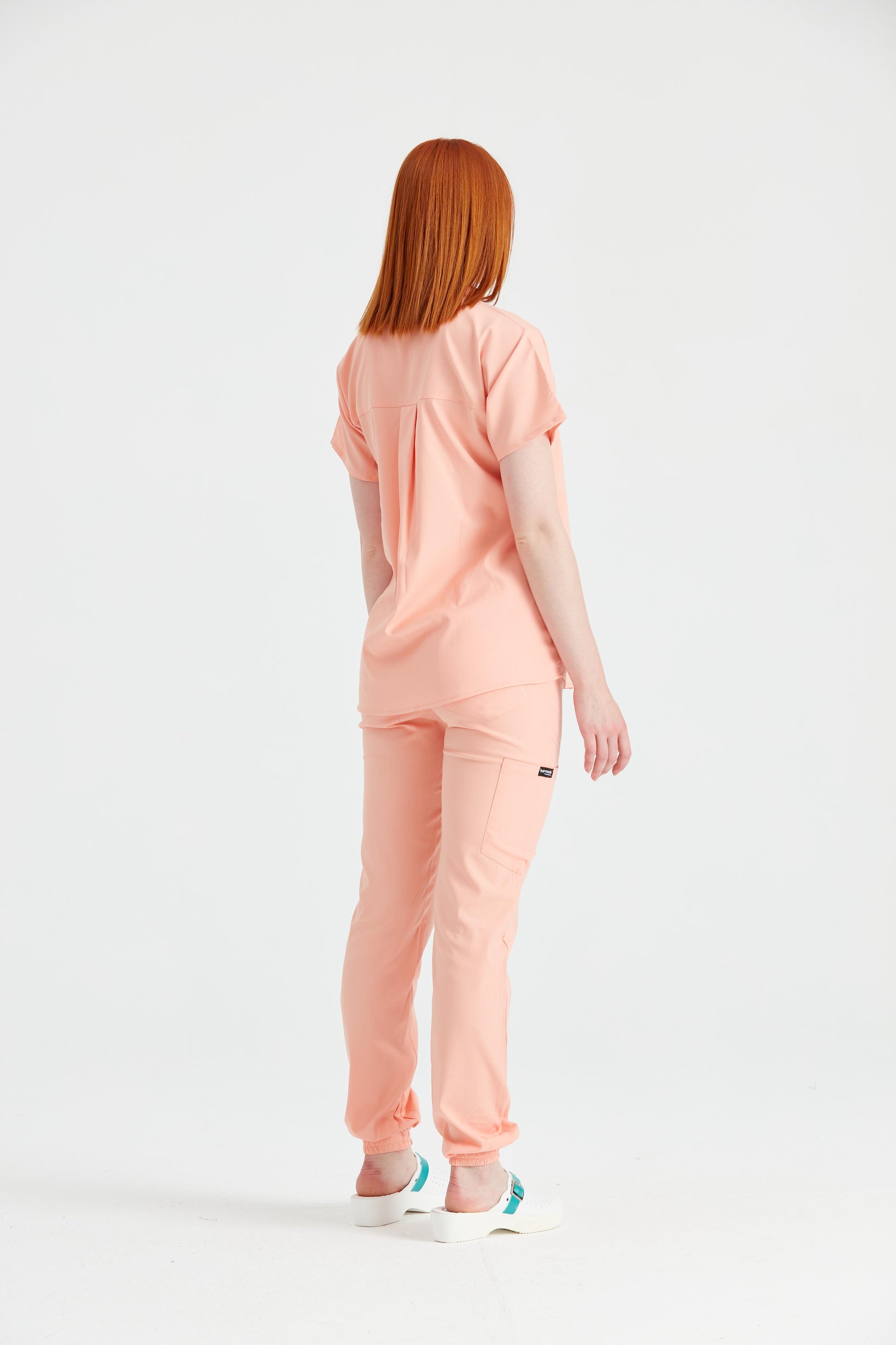 Asistenta medicala imbracata in costum medical de dama portocaliu, vedere din spate