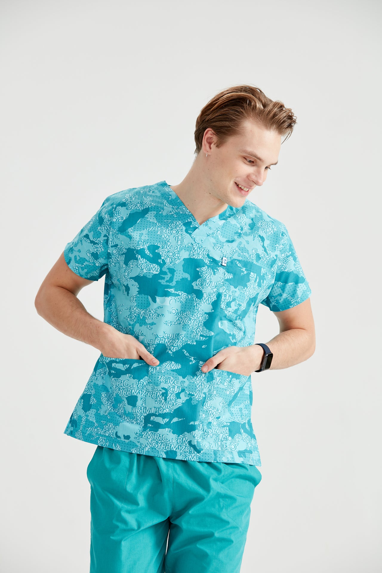 Asistent medical imbracat in bluza Turquoise Camouflage, cu mainile in buzunar, vedere din fata  