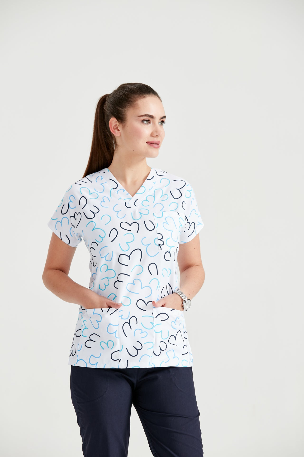 Asistenta medicala imbracata in bluza medicala alba Heart White, cu imprimeu, cu mainile in buzunar