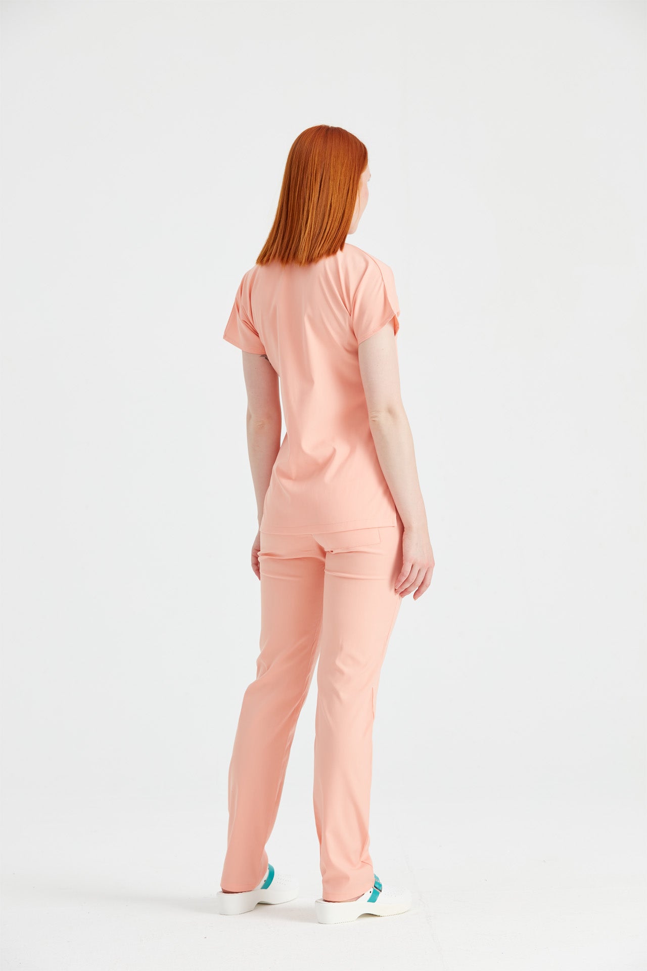 Asistenta medicala imbracata in costum elastan Peach, vedere din spate