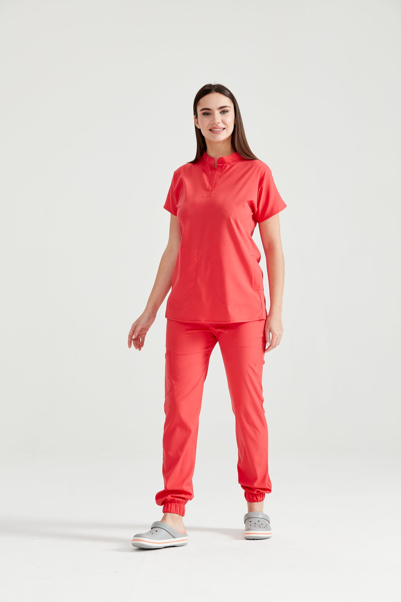 Asistenta medicala imbracata in costum medical de dama rosu corai, Coral, vedere din picioare
