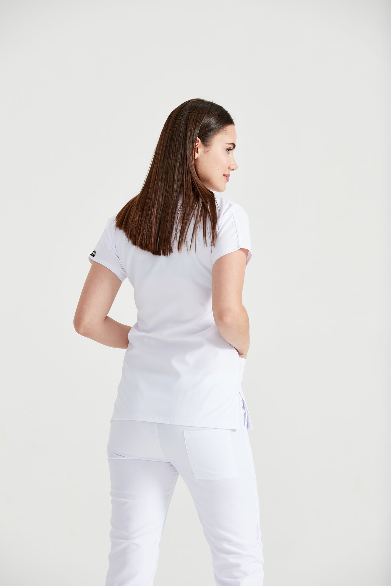 Asistenta medicala imbracata in costum clasic alb, vedere din spate