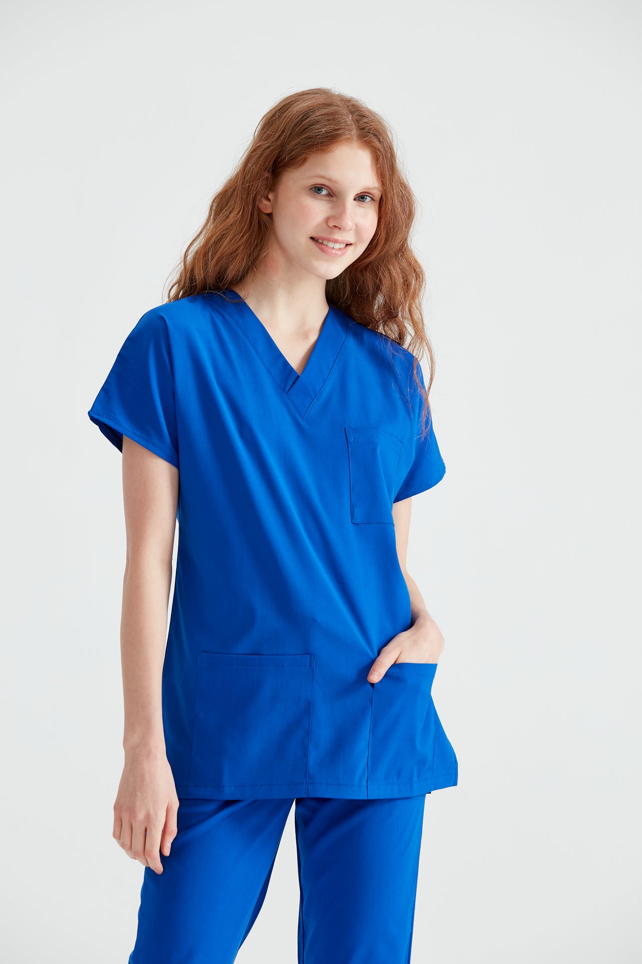  Asistenta medicala imbracata in costum medical albastru Royal, cu mainile in buzunar, vedere din fata