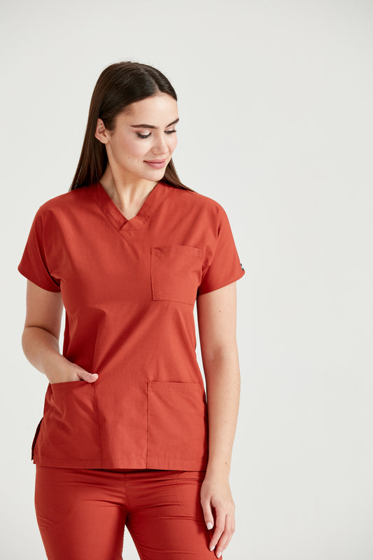 Asistenta medicala imbracata in costum medical rosu Classic Red, cu mainile in buzunar, vedere din fata