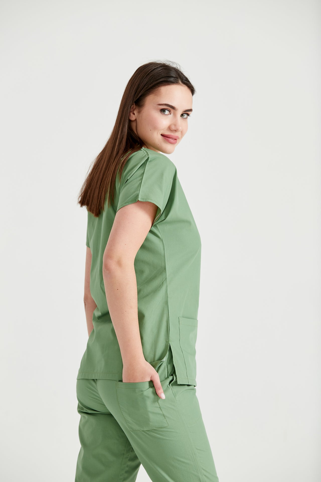 Asistenta medicala imbracata in costum medical verde fistic Pistaccio, vedere din semi-profil