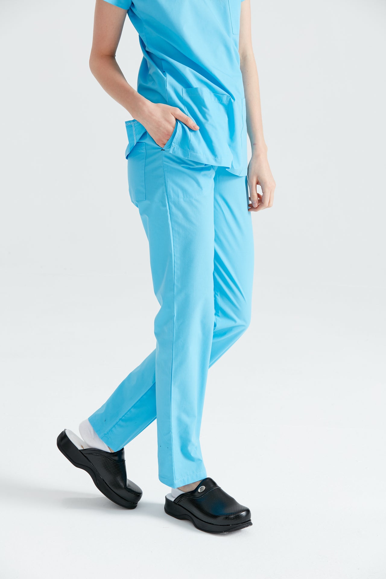 Asistenta medicala imbracata in pantaloni Turquoise, cu mana in buzunar, vedere din semi-profil